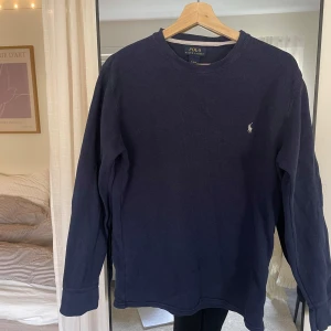 Mörkblå långärmad tröja från Polo Ralph Lauren - Mörkblå långärmad tröja från Polo Ralph Lauren med rund halsringning och diskret broderad logga på bröstet. 