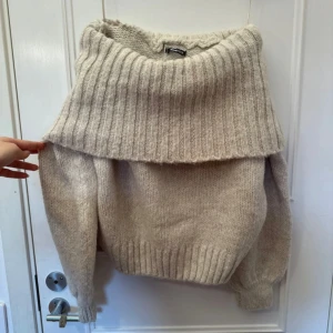 Beige stickad offshouldertröja från Gina Tricot - Supermysig beige stickad tröja från Gina  med bred ribbad krage som kan bäras offshoulder. Perfekt för kyliga dagar och enkel att styla med jeans eller kjol😍aldrig använd❤️