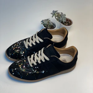 Maison Margiela Gats Paint Splatter  - Säljer nu dessa extremt fina par Maison Margiela Gats som är svarta och gjorde av mocha med multifärgad färgstänk på tålådan. Skorna är defekt fria förutom att det finns några gula fläckar på sulan som säker går att gnugga eller trampa bort. Nypris på skorna ligger på 8500kr+ och är underbart skick. Låda medföljer tyvär ej men bild på kvitto finns! Kom med prisförslag eller frågor! 🌴🍾