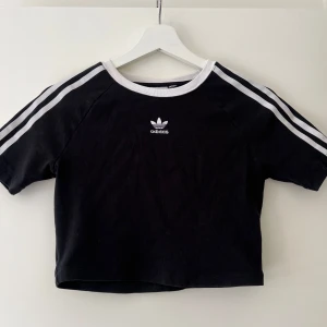 Svart croppad Adidas t-shirt  - Svart croppad t-shirt från Adidas. Använd två-tre gånger så i väldigt gott skick. Storlek passar XS-S. 