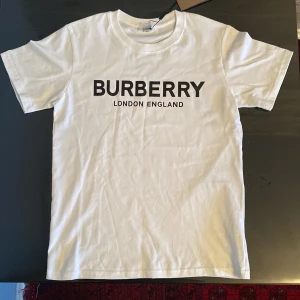 Vit t-shirt från Burberry - Burberry London England T-shirt som är väldigt snygg för sommaren. Som sätt är pris etiketten kvar fast box ingår ej. REPLIKA! Pris  går att diskuteras öppen för byten!