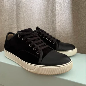 Svarta sneakers från Lanvin med vita sulor - Säljer ett par svarta sneakers från Lanvin med vita, platta sulor och rund tå. Klassisk och stilren design, perfekt till många outfits. Skorna kommer med original dustbags. Köptes på NK Göteborg för 5200 kr. Skick 8/10. 