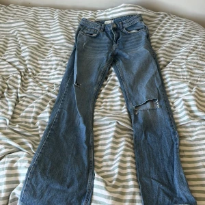 Blå jeansbyxor från Perfect Jeans - Säljer ett par klassiska blå jeansbyxor från Perfect Jeans i rak passform. Byxorna har normal midja, fem fickor och en lagad reva på ena benet. Perfekta för en avslappnad stil.