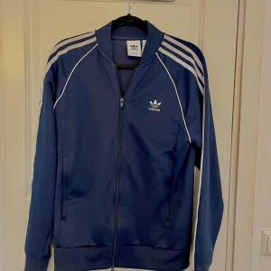 Blå aridas kofta - Säljer den skitnsygga koftan från adidas. Nypris runt 900kr. Passar S och M men är stl M. Den är äkta med qr kod som går att skanna. Använd typ tre ggr💓