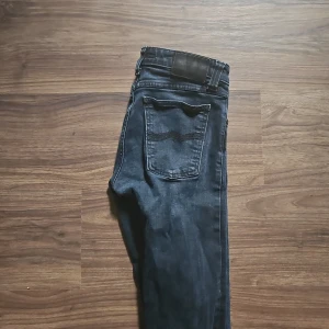 Mörkblå jeans från Nudie Jeans - Säljer ett par snygga mörkblå jeans från Nudie Jeans i bra skick. De har en klassisk femficksdesign och en bekväm passform. Perfekta för både vardag och fest! Säljer de på grund  av att de inte passar mig i storlek och sitter för tajt på mig. De är små i storleken. Kom gärna med frågor och funderingar. 
