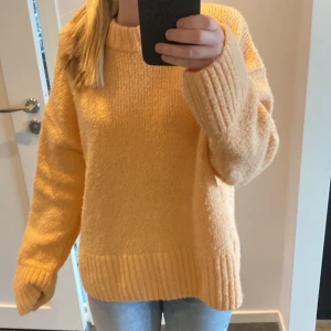 Orange stickad tröja - Är mer orange i verkligheten!! Mysig stickad tröja med grov ribbstickning vid ärmslut och nederkant. Tröjan har en avslappnad passform och långa ärmar, perfekt för kyligare dagar. Enkel och stilren design som passar till det mesta.