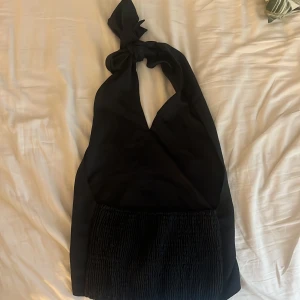 Halterneck topp  - Säljer en svart halterneck topp  med knyt i nacken. Perfekt för dig som vill ha en stilren och snygg outfit 