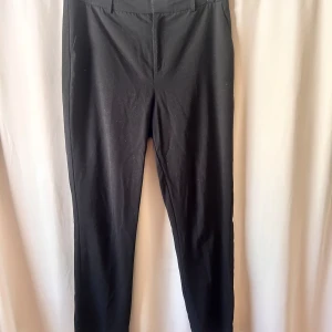 Kostymbyxor - Svarta kostymbyxor med normal passform och klassisk design. Byxorna har hällor för bälte och diskreta sidfickor. Lite noppriga och luddiga men det mesta bör försvinna med en ordentlig roller.