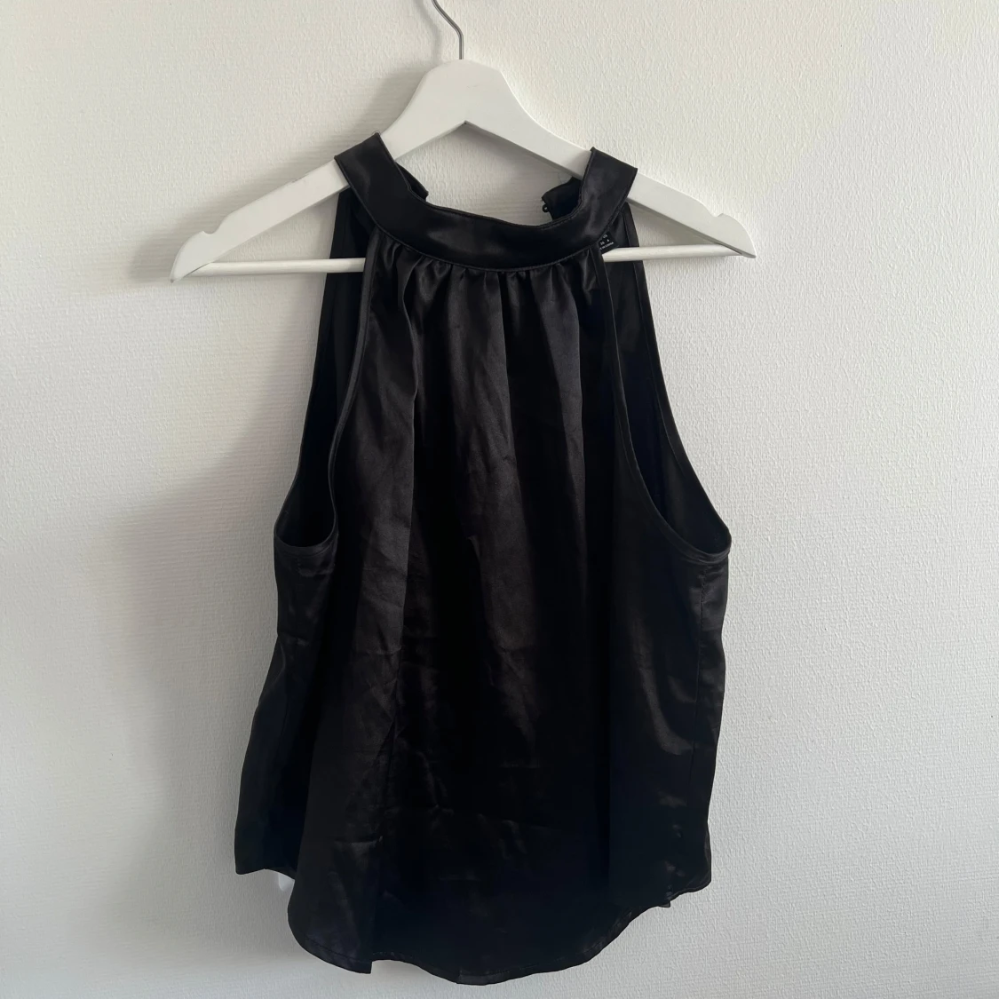 Svart ärmlös satinblus med hög krage