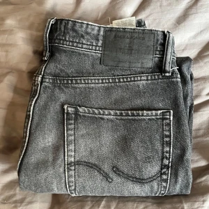 Grå och ljusblå jeans från Jack & Jones - Två par klassiska jeans från Jack & Jones, ett i tvättad grå och ett i ljusblå denim. Båda har raka ben, femficksdesign och tydliga sömmar på bakfickorna. Perfekta för en avslappnad stil. 99 kr för ett par 175 kr för båda! Storlek 29/32