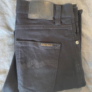 Svarta jeansbyxor från Nudie Jeans - Säljer ett par svarta jeans från Nudie Jeans.Perfekta för dig som gillar stilrena och tidlösa jeans. Storlek W29 L 30 i riktigt bra skick. Hör av er vid intresse!!