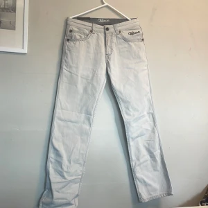 Ljusgrå jeansbyxor från Release - Snygga ljusgrå jeansbyxor från Release med raka ben och klassisk femficksdesign. Byxorna har broderad logga på insidan av linningen och silverfärgade nitar. Perfekta för en stilren och avslappnad look.