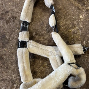 Grimma för häst - Mysigt och mjuk grimma med beige fuskpäls, perfekt för att ge extra komfort till hästen. Har svarta spännen och justerbara remmar för bra passform. 