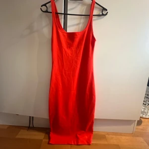 Orange tight  klänning - Säljer en orange tajt klänning, ser lite röd ut men den är orange irl. Har en svart likadan klänning så tog den som exempel på hur klänningen ser ut på då jag inte har bild med den orangea på. Jag var 165 på bilderna och klänningen stannade över mina knän! 