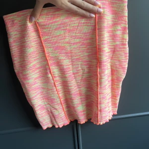 Färgglad ribbad kjol - En kortkjol i ribbat material med ett färgstarkt mönster i rosa, gul och vit. Kjolen har en rak passform och är perfekt för dig som gillar att sticka ut med din stil.
