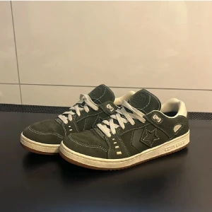 Gröna Converse CONS sneakers 43 - Säljer ett par gröna Converse CONS sneakers med vita snören och vit sula. Skorna har klassisk stjärnlogga på sidan och 'CONS' broderat på hälen. Perfekta för dig som gillar streetwear och vill ha en stilren sneaker med retrovibbar.