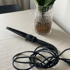 Svart locktång från CeraWand - En svart konformad locktång från CeraWand med lång sladd. Handtaget är ergonomiskt och tången har en matt finish. Perfekt för att skapa mjuka lockar eller vågor. Modell: RM-C01-V32.