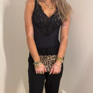 Svart spetsbody med v-ringning - Säljer ett svarta bodyn med v-ringning och spetsdetaljer upptill. Linnet har smala axelband och är figurnära i modellen. Perfekt att styla med både byxor och kjol för en trendig look. Kostym från BIKBOK och bodyn är helt ny använd en gång från hunkemöller