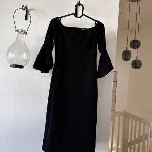 Svart långklänning med vida ärmar - Säljer en elegant svart långklänning med fyrkantig ringning och vida trekvartsärmar. Klänningen har en stilren och klassisk design som passar perfekt till speciella tillfällen.