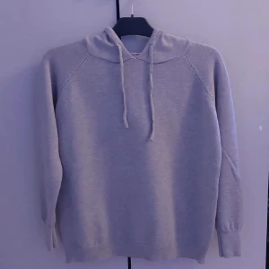 Grå Kashmir hoodie  - En enkel och stilren grå hoodie med huva och dragsko. Tröjan har långa ärmar och ribbade muddar vid ärmslut och nederkant. Perfekt för en avslappnad look.