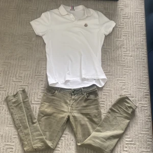 Vit piké t-shirt från Moncler - Säljer en klassisk vit piké t-shirt från Moncler med broderad logga på bröstet. T-shirten har korta ärmar och krage med knappar. Perfekt för en clean och stilren look. Storlek XL men skulle passa L också. Modellen är 176cm och väger 68kg och tröjan är lite stor på han. OBS! Ej säker på äkthet då den köptes här på plick! Vid funderingar är det bara att skriva! 