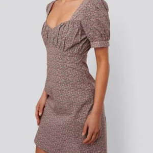 Blommig kortklänning med puffärm - Supersöt kortklänning med småblommigt mönster i rosa och grönt på beige botten. Klänningen har puffiga kortärmar, markerad byst och fyrkantig ringning. Perfekt för vår och sommar!