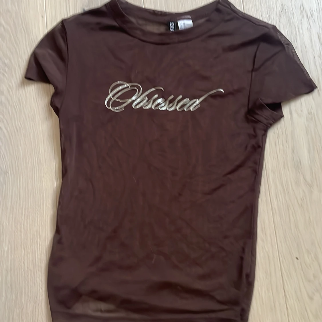 Brun mesh topp med texten 'Obsessed' från Divided