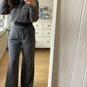 Grå vida byxor med resårmidja M oanvända  - Säljer ett par grå byxor med bred resår i midjan och raka, vida ben. Byxorna har en avslappnad passform och är perfekta för en chill och stilren look. Passar till både enkla toppar och stickade tröjor.