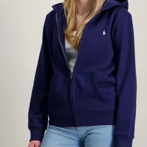 Ralph Lauren hoodie - Mörkblå hoodie med dragkedja från Ralph Lauren. Klassisk modell med huva och fickor framtill. Perfekt för en avslappnad och stilren look.