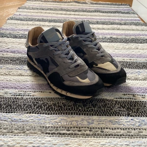 Valentino rockrunners - Säljer ett par snygga Valentino rockrunners i grått och svart med camouflage-mönster. Alla studsen på skorna finns kvar. Mockan har bra färg men kan möjligen borstas upp lite, samt har tyget lite fläckar men inga permanenta defekter. Inköpta från High End Sweden på facebook för 2000kr, tyvärr ingen låda eller dustbag men skorna är äkta och köpta från en legit checkad försäljare på sidan. I och med att ingen låda eller dustbag finns kan priset diskuteras.
