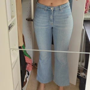 Ljusblå bootcut jeans från FK Jeans - Filippa K Hally jean 26602. Säljer ett par ljusblå bootcut jeans från FK Jeans med medelhög midja. Jeansen har klassisk femficksdesign, raka ben med utsvängd nederdel och stängs med dragkedja och knapp. Perfekta för dig som gillar retrovibbar och en avslappnad stil.