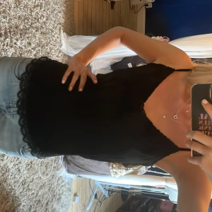 Svart linnetopp med spets från Odd Molly - Supersnygg svart linnetopp från Odd Molly med tunna axelband och spetsdetaljer längs urringning och nederkant med liten rosett där fram. Perfekt att styla till jeans eller kjol 💞💞använd en gång☀️