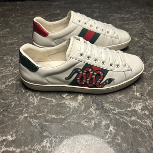 Gucci ace - Säljer ett par otroligt snygga Gucci ace! Skorna är i bra skick och vid köp inkluderas dustbag och såklart skorna. Nypris ligger över 9000kronor men vi säljer dessa för endast 2199 och kan gå ner i pris vid snabb affär! Skorna är givetvis äkta och är i storlek 41. Skorna har en liten fläck mitt på vänsterskon (kolla bild 2). Skriv gärna ifall det är några funderingar, allt bästa SkoKapet