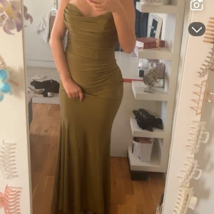 Olivgrön balklänning - En super fin balklänning. HELT OANVÄND. (Min bal ställdes in så vill sälja så fort som möjligt) klänningen sitter så fint på kroppen & är lång precis som man vill ha det :)