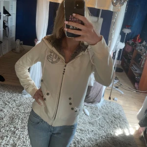 Vit hoodie från Guess Jeans - En vit hoodie från Guess Jeans 1981 Los Angeles med fuskpälsfoder i luvan och insidan. Jackan har dragkedja, dekorativa knappar och broderad logga på bröstet och därbak. Jättefin och riktigt snygg till jeans! Nyskick, säljer då den ej kommit till användning💓☀️