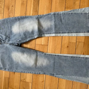 Blå jeans från Gallery Dept. - Säljer ett par blå jeans från Gallery Dept. med ljusa slitningar och raka ben. Jeansen har klassisk femficksdesign, knappgylf och bälteshällor. Snyggt blekta partier framtill och baktill för en cool vintagekänsla.