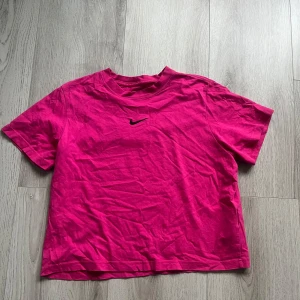 Rosa Nike t-shirt - Säljer en rosa t-shirt från Nike med klassisk svart på bröstet. Modellen är loose fit och har korta ärmar. Perfekt för en avslappnad stil och enkel att matcha med jeans eller shorts. Tröjan är i storlek XL men passar mig som har S/M i storlek och är i mycket mycket bra skick.Säljer den då jag inte använder tröjan och tror att någon annan kommer använda den mer.Original priset är 300kr,säljer den för 200kr