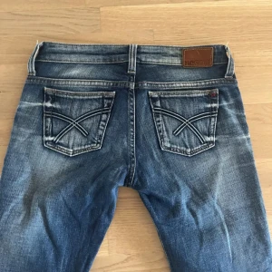 Blå jeans från Big Star - Säljer ett par blåa jeans från Big Star med kontrastsömmar på bakfickorna. Jeansen är lågmidjade och bootcut/raka i benen 