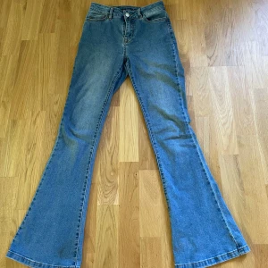 Blå bootcut jeans från Vila - Säljer ett par klassiska blå bootcut jeans från Vila i storlek XS. Jeansen har hög midja/ mitt emellan och utsvängda ben.