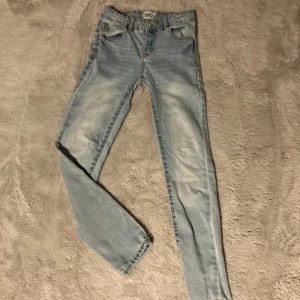 Ljusblå skinny jeans från lager157 - Säljer ett par ljusblå skinny jeans från lager157 i storlek 160. Jeansen har klassisk femficksdesign, knapp och dragkedja framtill samt något slitna detaljer för en cool look. Perfekta till vardags och lätta att matcha med olika toppar.