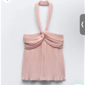 Ljusrosa plisserad halterneck topp - Säljer en ljusrosa halterneck topp med plisserat tyg och twistad detalj framtill. Toppen har en elegant och luftig känsla med breda axelband som knyts i nacken. Perfekt för varma dagar eller festliga tillfällen.