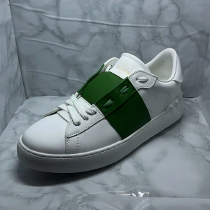 Valentino Garavani Open sneakers med grönt band - Säljer ett par vita Valentino Garavani Open sneakers med grönt band. Pris går att diskuteras vid snabbt köp!