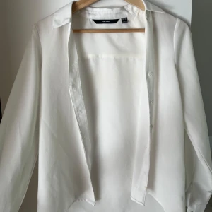 Vit skjorta  - Klassisk vit skjorta Vero Moda  med krage och knappar framtill. Skjortan har lång ärm och är tillverkad i ett tunt, mjukt material som känns skönt mot huden. Perfekt att styla lager på lager eller bära som den är. Använd fåtal gånger💕