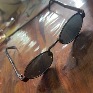 Svarta ovala solglasögon - Snygga svarta solglasögon med ovala glas och smala bågar. Glasögonen har en minimalistisk design och passar perfekt för en trendig look. Bågarna är i svart plast och glasen är mörka. Lite böjd de sista bilden men sitter bra 