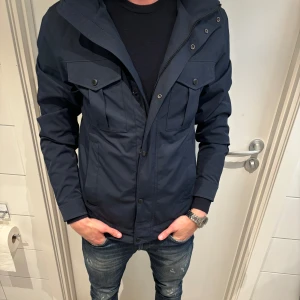 Mörkblå vindjacka från J.Lindeberg - Säljer nu min skit feta j lindberg bailey field jacka SENASTE MODELLEN,  super skick och perfekt att ha till sommarkvällar 