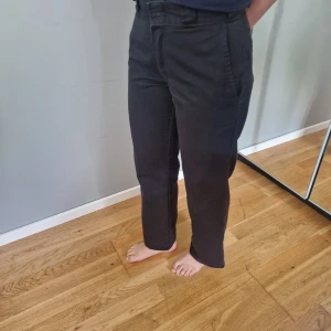 Svarta byxor från Dickies - Säljer ett par svarta byxor från Dickies med klassisk rak passform och diskreta fickor. Byxorna har hällor för bälte och stängs med dragkedja och knapp. Perfekta för en clean och stilren look.