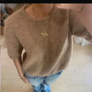 Beige stickad tröja med kort ärm - Mysig beige stickad tröja med korta ärmar och rund halsringning. Den är storlek M men skulle säga att det är mer som en S!