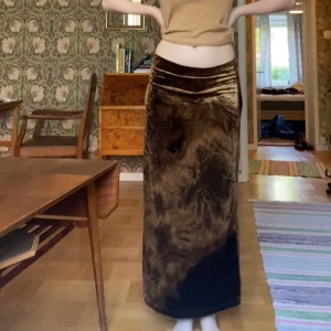 Brun sammet långkjol från B-Young - Säljer en brun långkjol i sammet från B-Young. Kjolen har en mjuk och glansig yta med ett unikt mönster i olika bruna nyanser. Den har rak passform och är perfekt för dig som vill ha något snyggt och bekvämt.