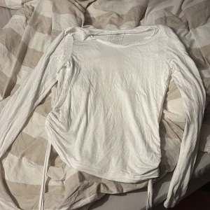 Vit långärmad topp med knyt i sidan - Säljer en vit långärmad topp från C i storlek S. Toppen har rund halsringning och knytband i sidorna för en snygg detalj. Tillverkad i mjuk viskos som känns skön mot huden. Perfekt till jeans eller kjol! Har inte använt denna för har känt att den är lite för genomskinlig men annars jätteskön tröja!