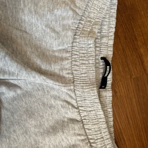 Grå mjukisbyxor från Bik Bok - Säljer ett par ljusgrå lowwaist mjukisbyxor från Bik Bok i storlek S. Byxorna har resår i midjan och är tillverkade i mjukt bomullsmaterial. Perfekta för en avslappnad stil och sköna att ha på sig hela dagen.